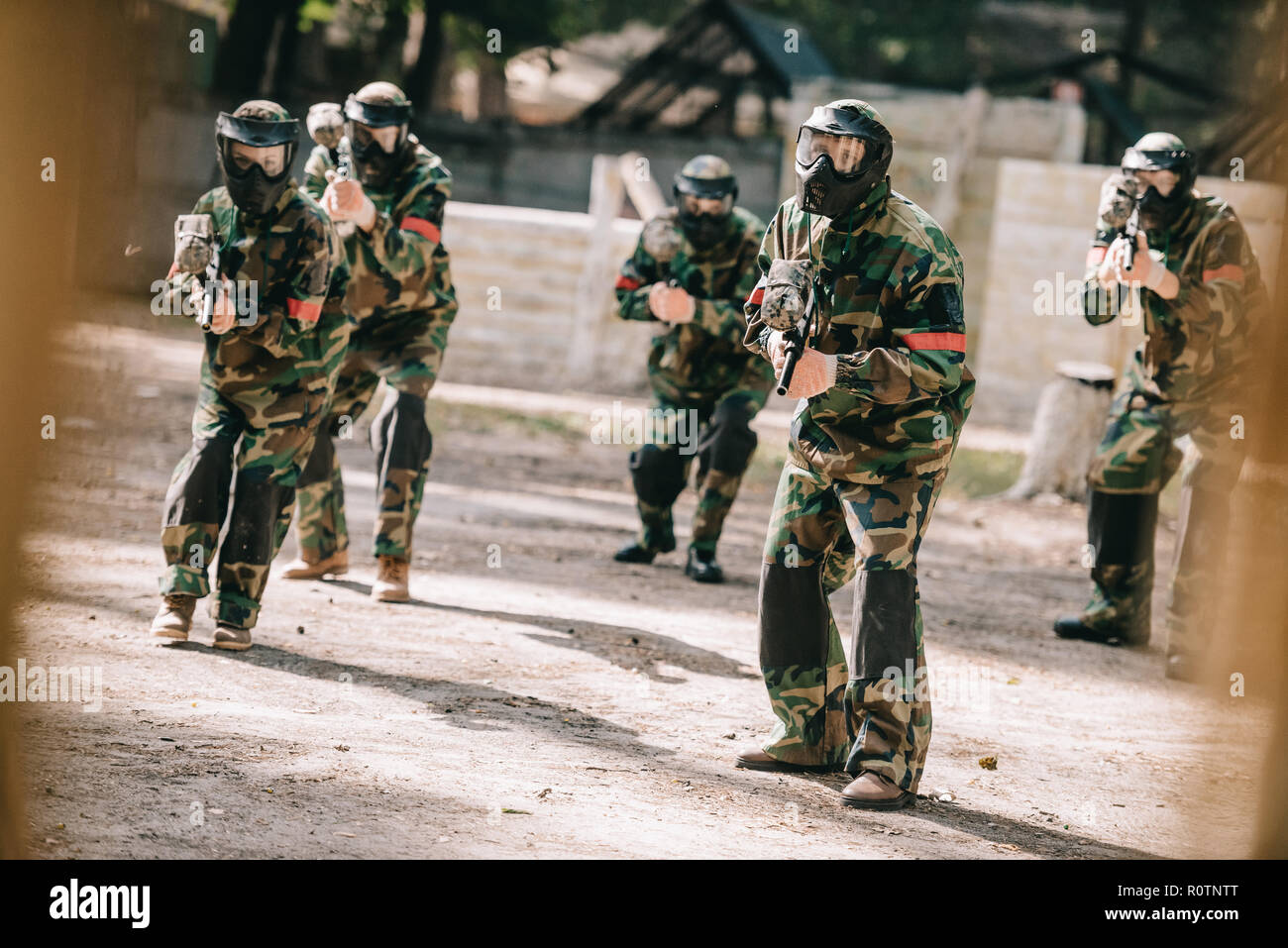 Il paintball team in uniforme e maschere protettive giocando a paintball con pistole marcatore all'aperto Foto Stock