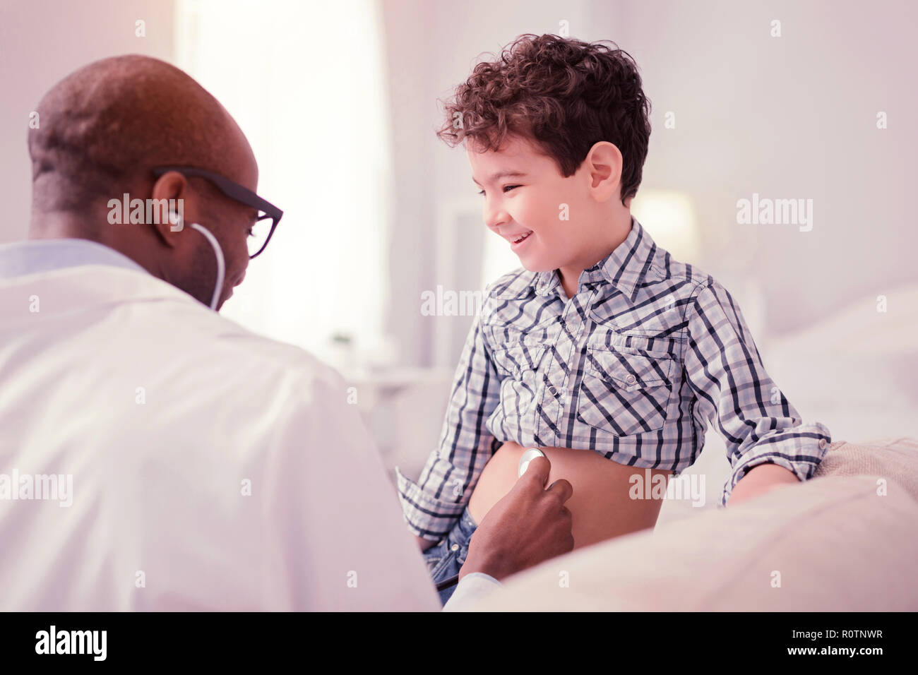Felice ragazzo positiva avente divertimento durante la visita di un medico Foto Stock