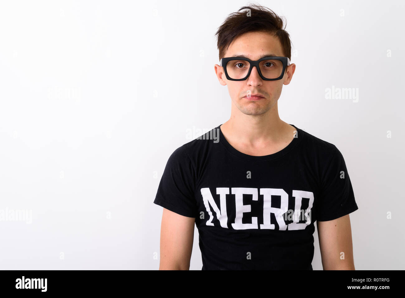Close up di giovani nerd uomo che indossa occhiali contro il retro bianco Foto Stock