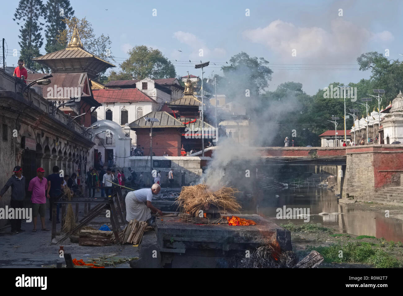 Al Tempio di Pashupatinath vicino al fiume Bagmati a Kathmandu, Nepal, un uomo dalla casta Dom 'intoccabile' conduce una cremazione indù Foto Stock