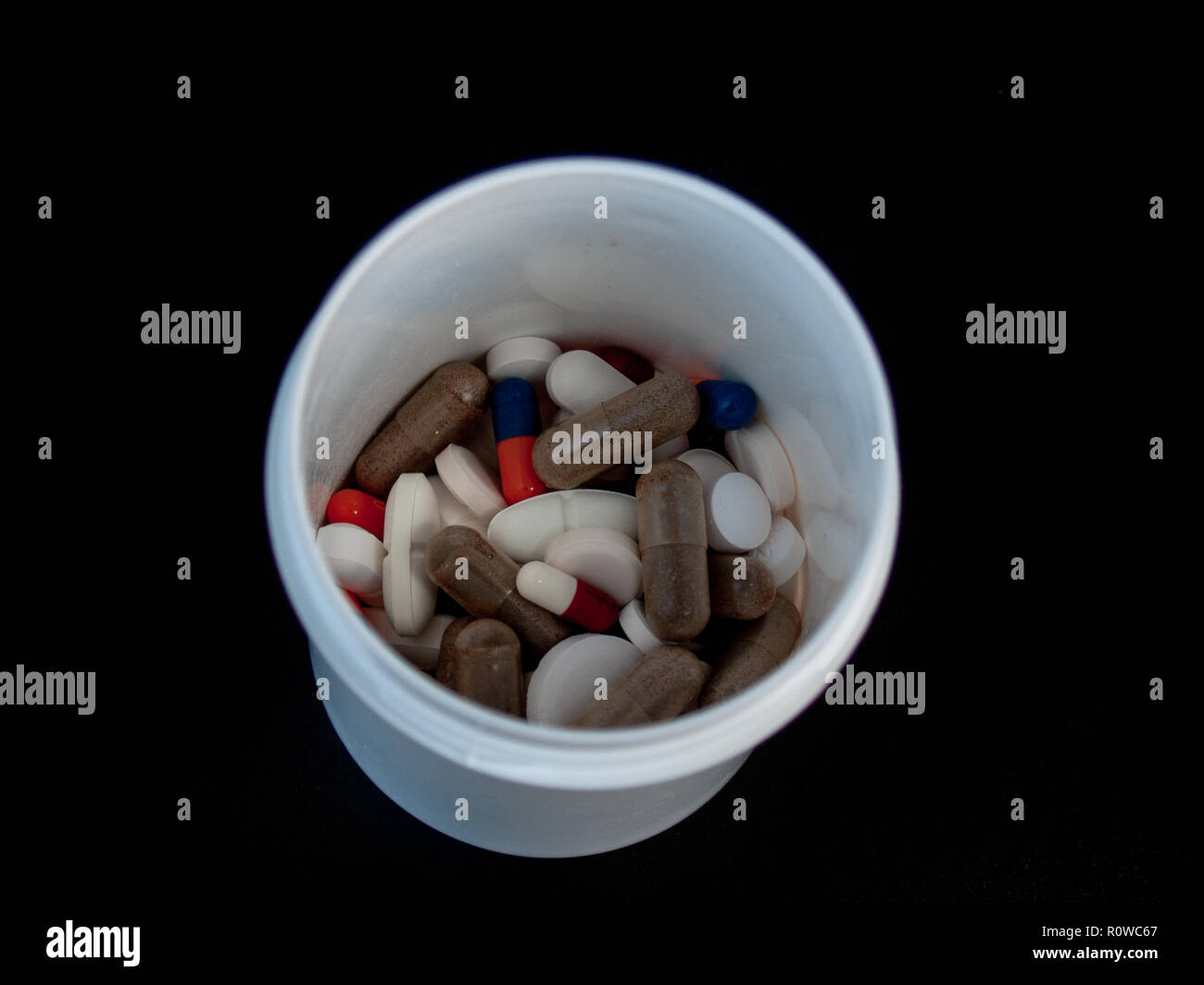 Una pentola di pillole di varie dimensioni, forme e colori. Concetto di salute Foto Stock