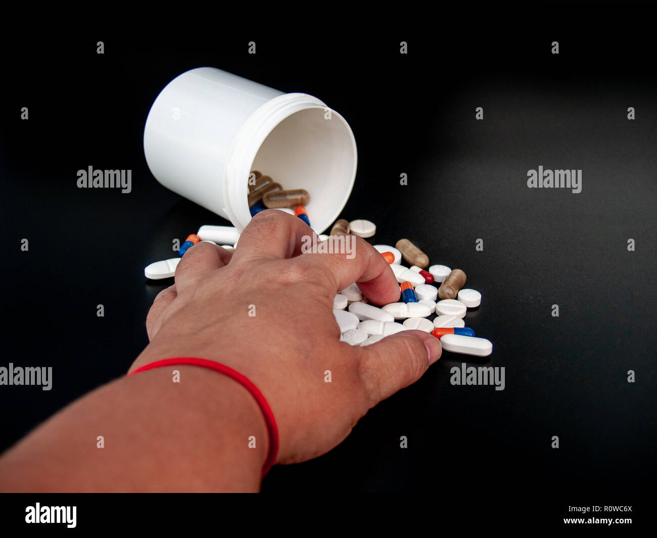 Una persona in possesso di pillole di varie dimensioni, forme e colori con la sua mano. Concetto di salute Foto Stock