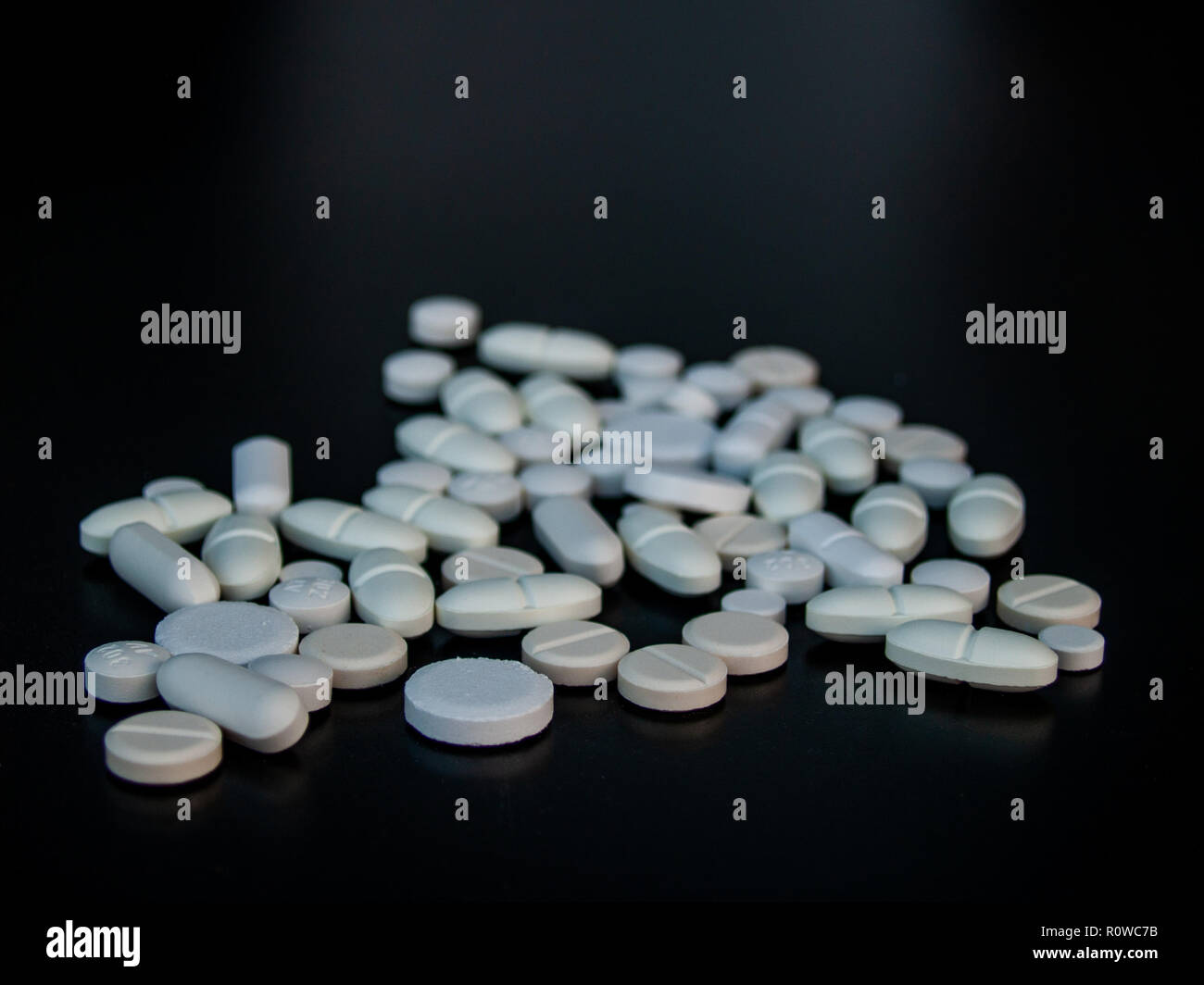 Pillole di diverse dimensioni, forme e colori con sfondo nero. Concetto di salute Foto Stock