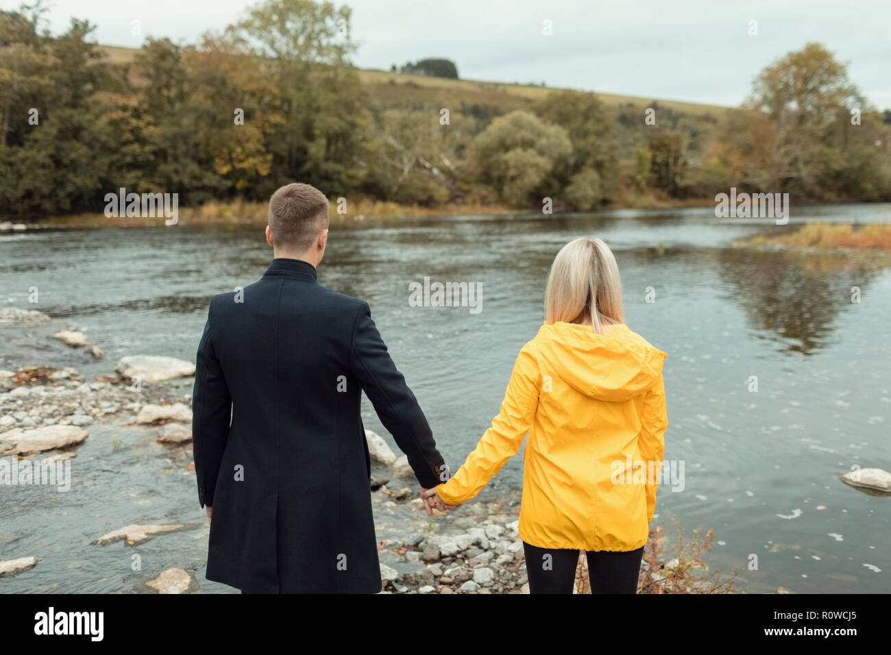 Giovane tenendo la mano e in piedi vicino al fiume Foto Stock