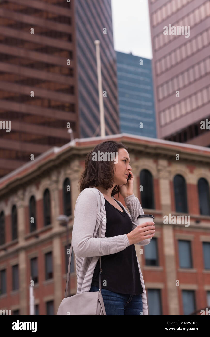 Donna con caffè mentre parlano al telefono cellulare Foto Stock