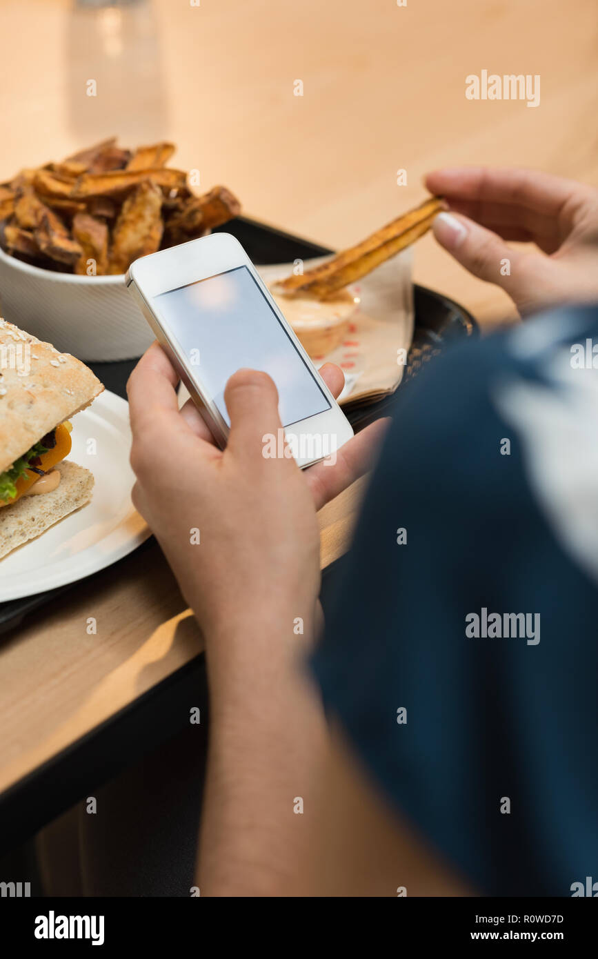 Donna con cibo mentre si utilizza il telefono cellulare nel ristorante Foto Stock