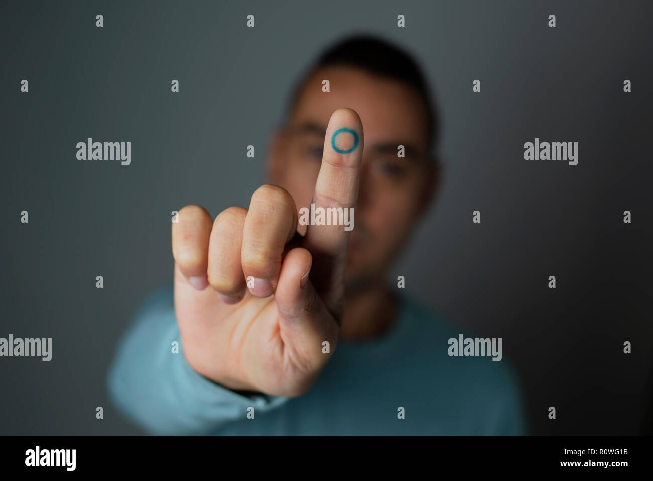 Primo piano di un giovane uomo caucasico con un cerchio blu, simbolo del diabete, nel suo indice, a sostegno di questa malattia Foto Stock