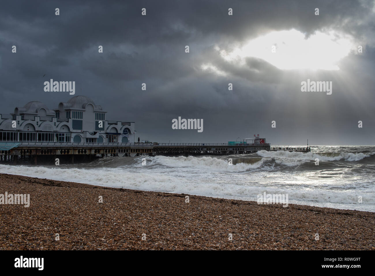 I raggi di luce su un molo britannico su un giorno di tempesta in mare Foto Stock