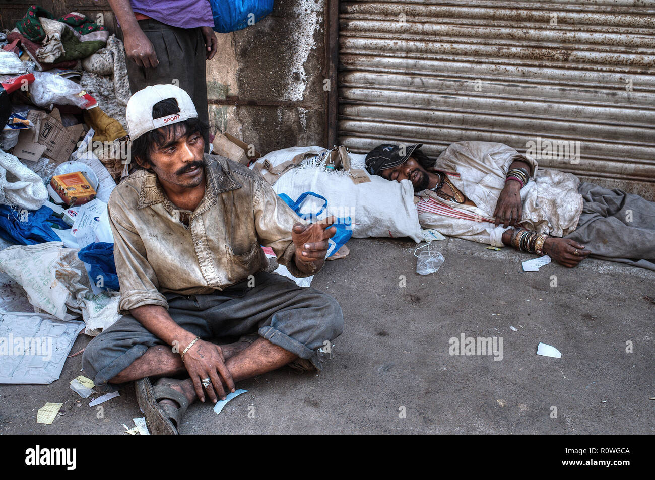 Tossicodipendenti in una corsia filth-sparged nella famigerata zona di Dongri di Mumbai, India, principalmente usando una versione economica di eroina chiamata 'zucchero di canna' Foto Stock