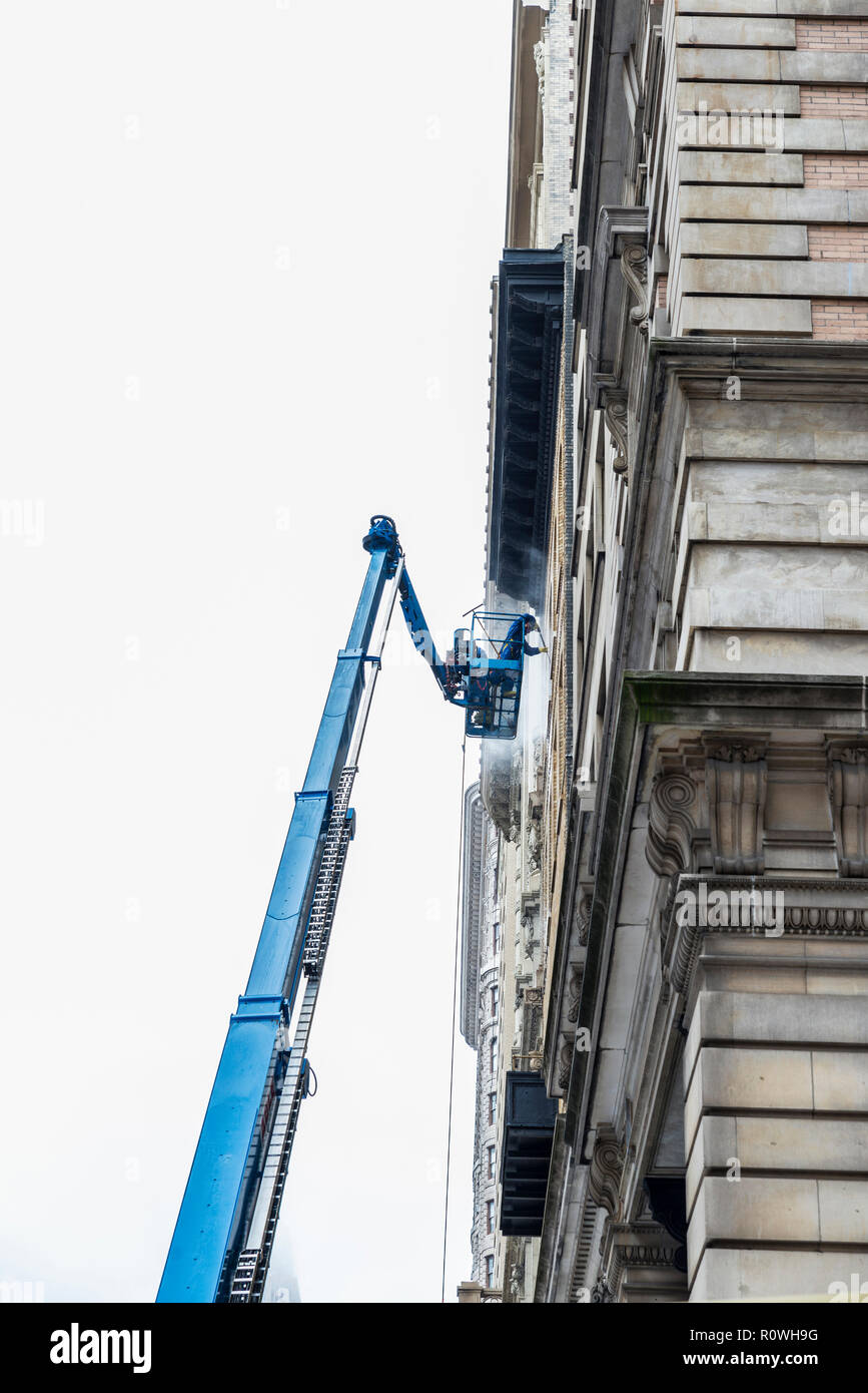 La città di New York, Stati Uniti d'America - Luglio 25, 2018: lavori di pulizia su una facciata di un grattacielo sulla Quinta Avenue con una gru e dei lavoratori nella città di New York, Stati Uniti d'America Foto Stock