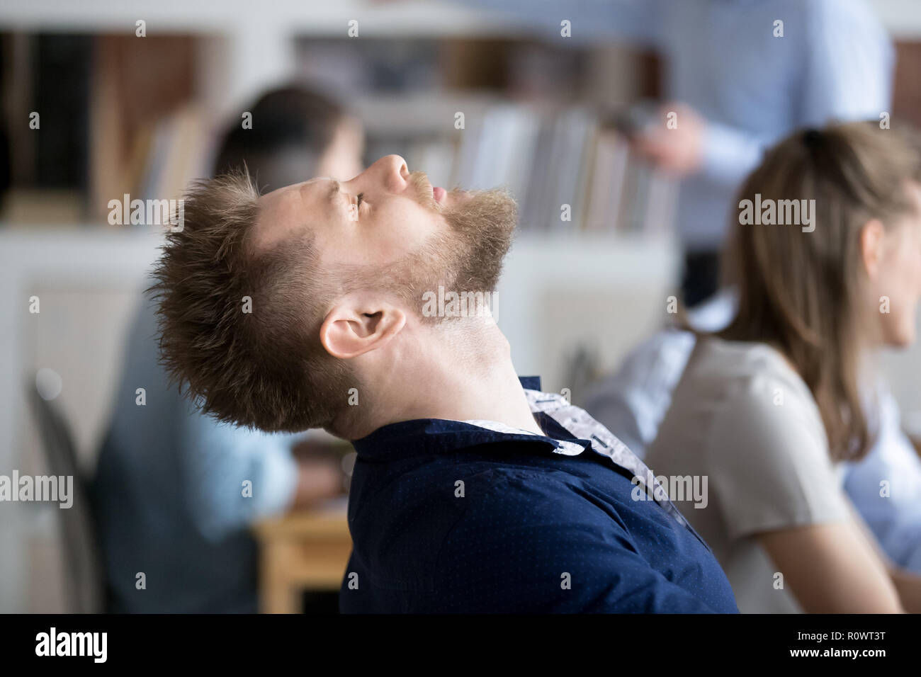 Stanchi dei dipendenti di sesso maschile di addormentarsi in cattedra al posto di lavoro Foto Stock