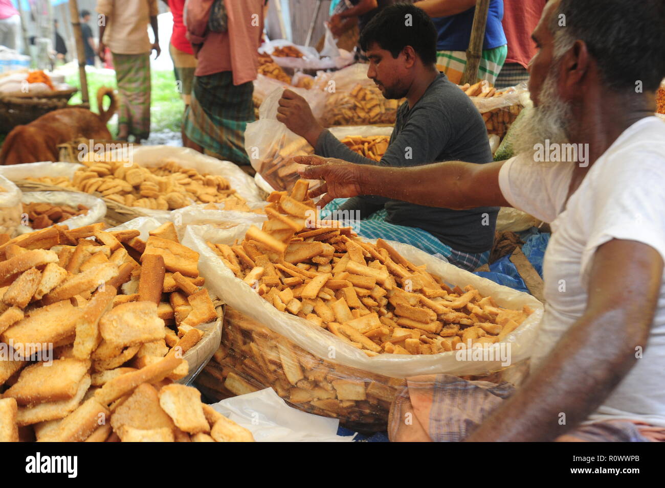 Un negoziante in attesa per i clienti di vendita i biscotti fatti in casa a Kaikkarateke mercato settimanale, Narayanganj distretto in Bangladesh. Settimanale mercato di villaggio Foto Stock