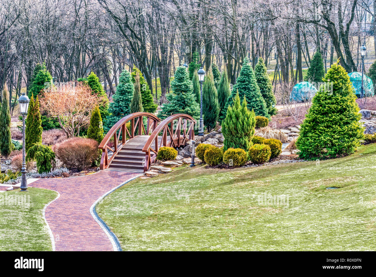 Frammento del parco in Mezhigiye vicino a Kiev. Bellissimi alberi e cespugli, un frammento del lago e un bel ponte attraverso un piccolo fiume. Foto Stock