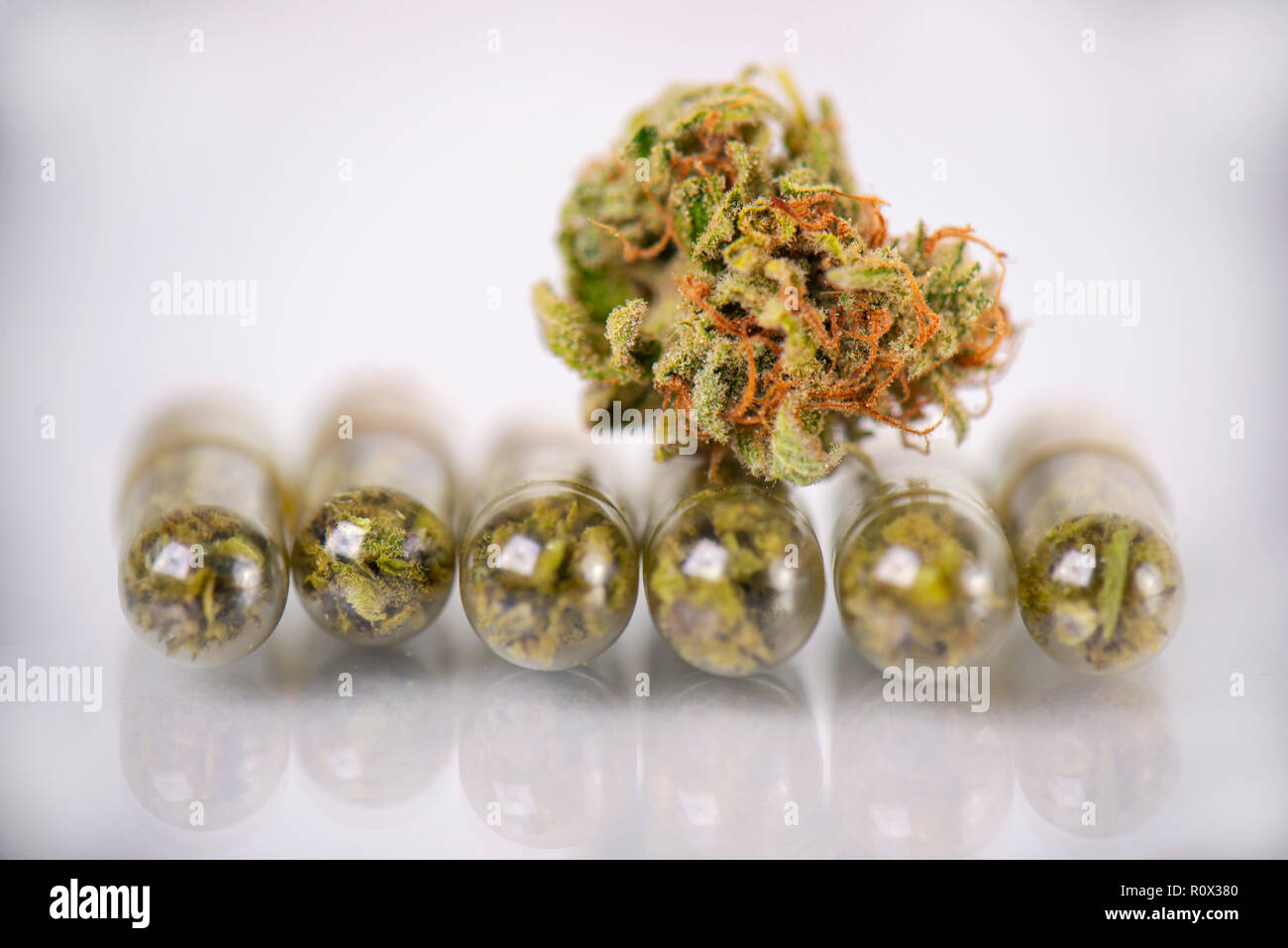 La marijuana medica concetto a secco con la cannabis bud e pillole isolato su bianco superficie riflettente Foto Stock