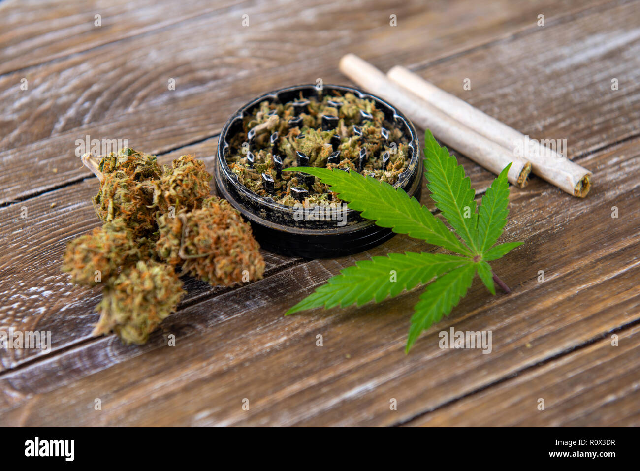 La Cannabis giunti con carta di laminazione e macinare su uno sfondo di legno Foto Stock