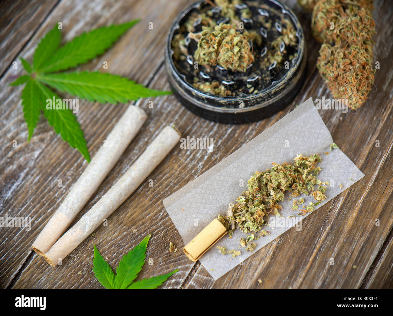 La Cannabis giunti con carta di laminazione e macinare su uno sfondo di legno Foto Stock