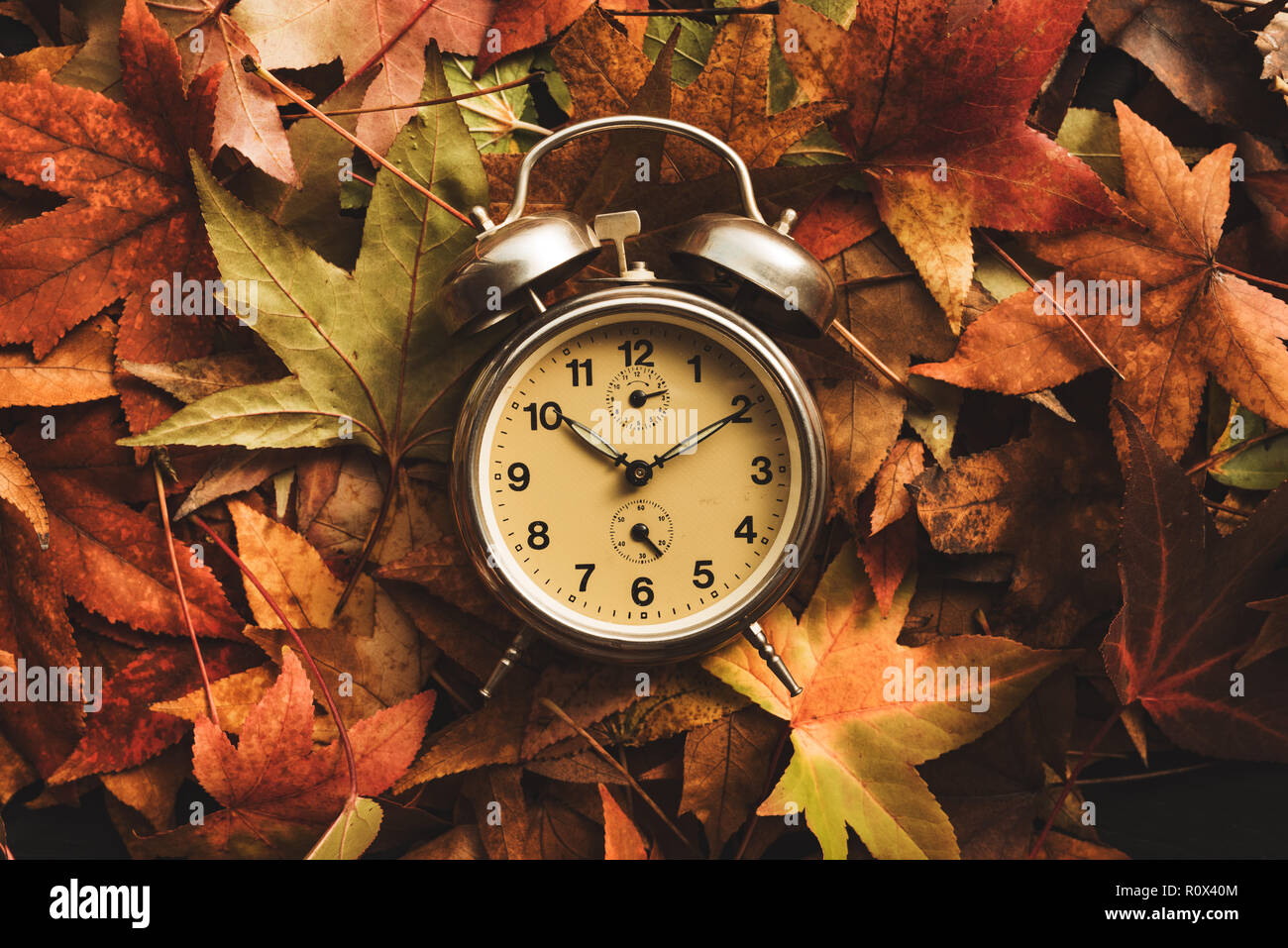 La stagione autunnale tempo, retro vintage sveglia in dry cadono le foglie - ora legale concept Foto Stock