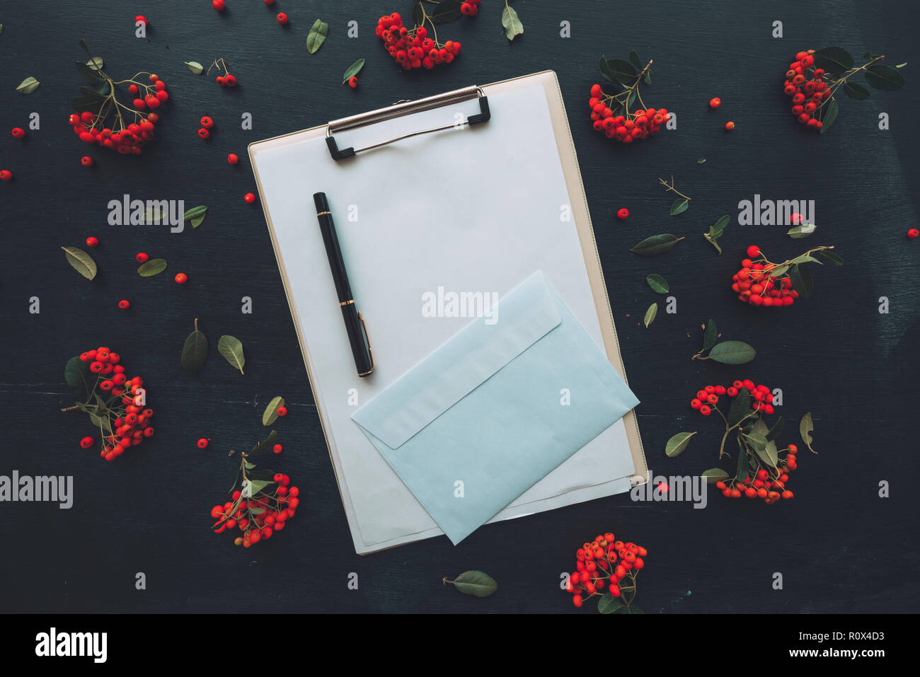 Piatto appunti laici notepad e busta, vista dall'alto mock up copia spazio per la scrittura di lettere su sfondo scuro decorata con frutti di bosco frutta arran Foto Stock