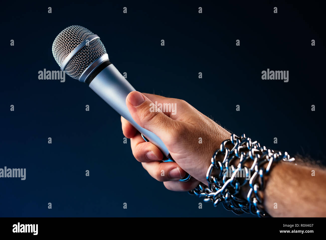 La libertà di stampa e il giornalismo, immagine concettuale con microfono in mano maschio legato con catene, bassa immagine chiave Foto Stock