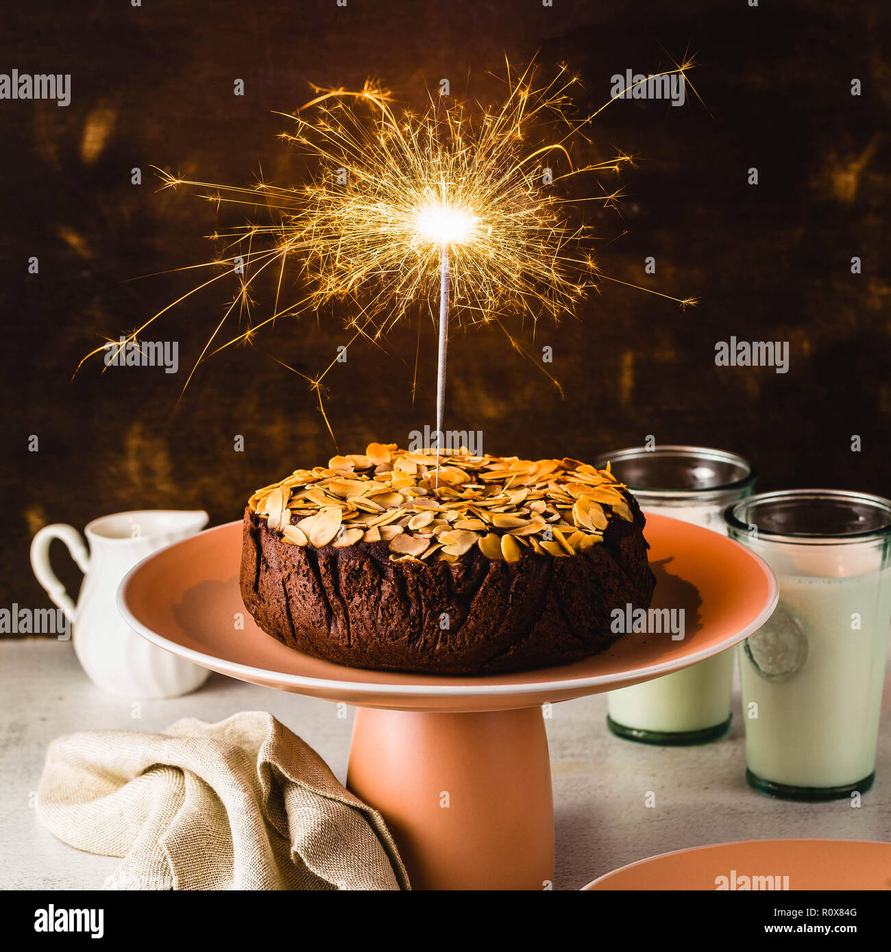 Senza glutine e vegano mandorla cioccolato paleo torta sul tavolo con la masterizzazione di festosa sparkler Foto Stock