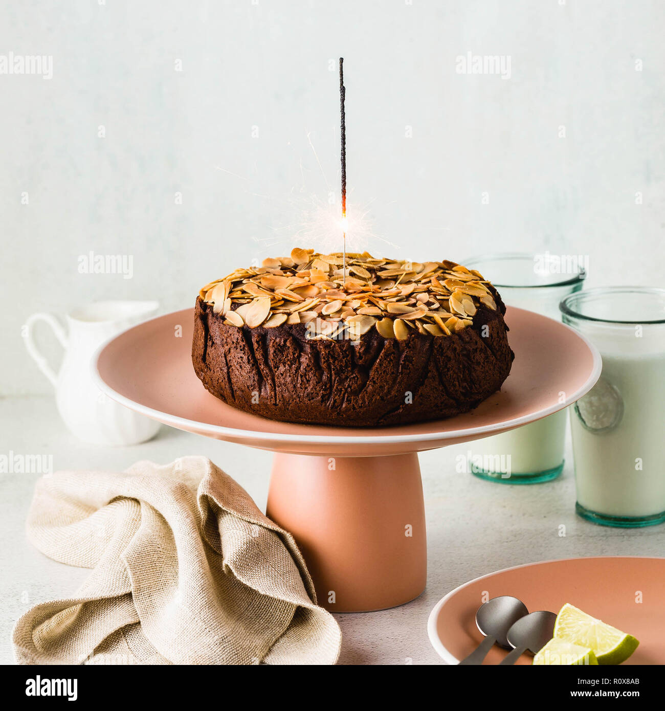 Senza glutine e vegano mandorla cioccolato paleo torta sul tavolo con la masterizzazione di festosa sparkler Foto Stock