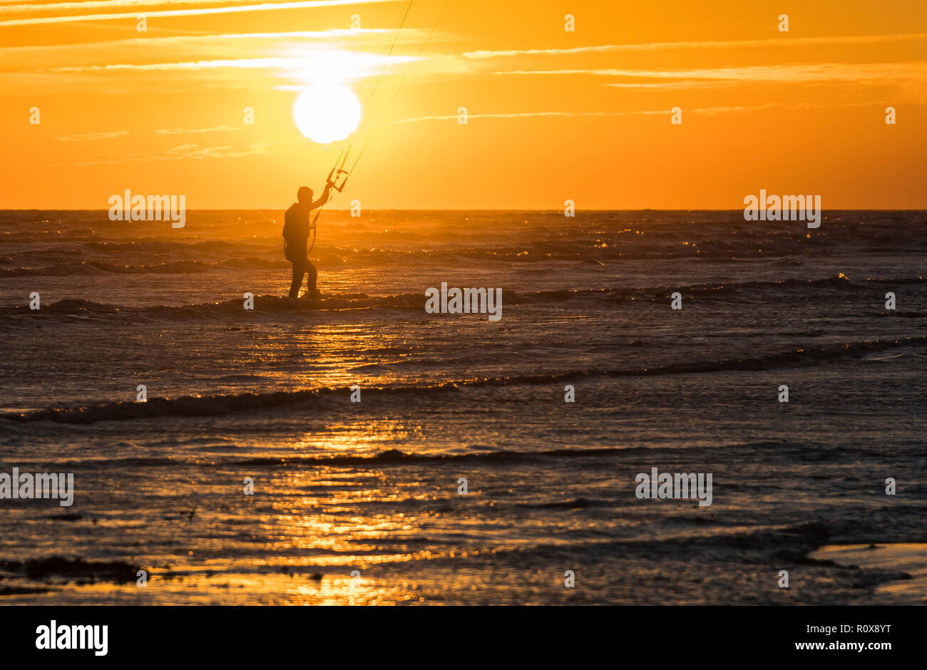 Silhouette di kitesurfer nella parte anteriore del tramonto sul mare in autunno nel West Sussex, Regno Unito. Foto Stock