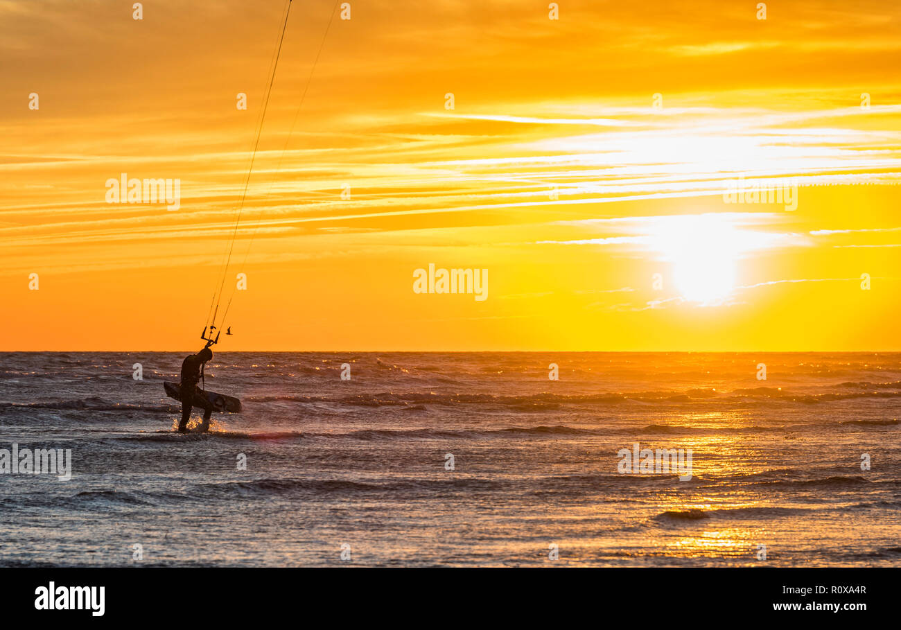 Silhouette di kitesurfer nella parte anteriore del tramonto sul mare in autunno nel West Sussex, Regno Unito. Foto Stock