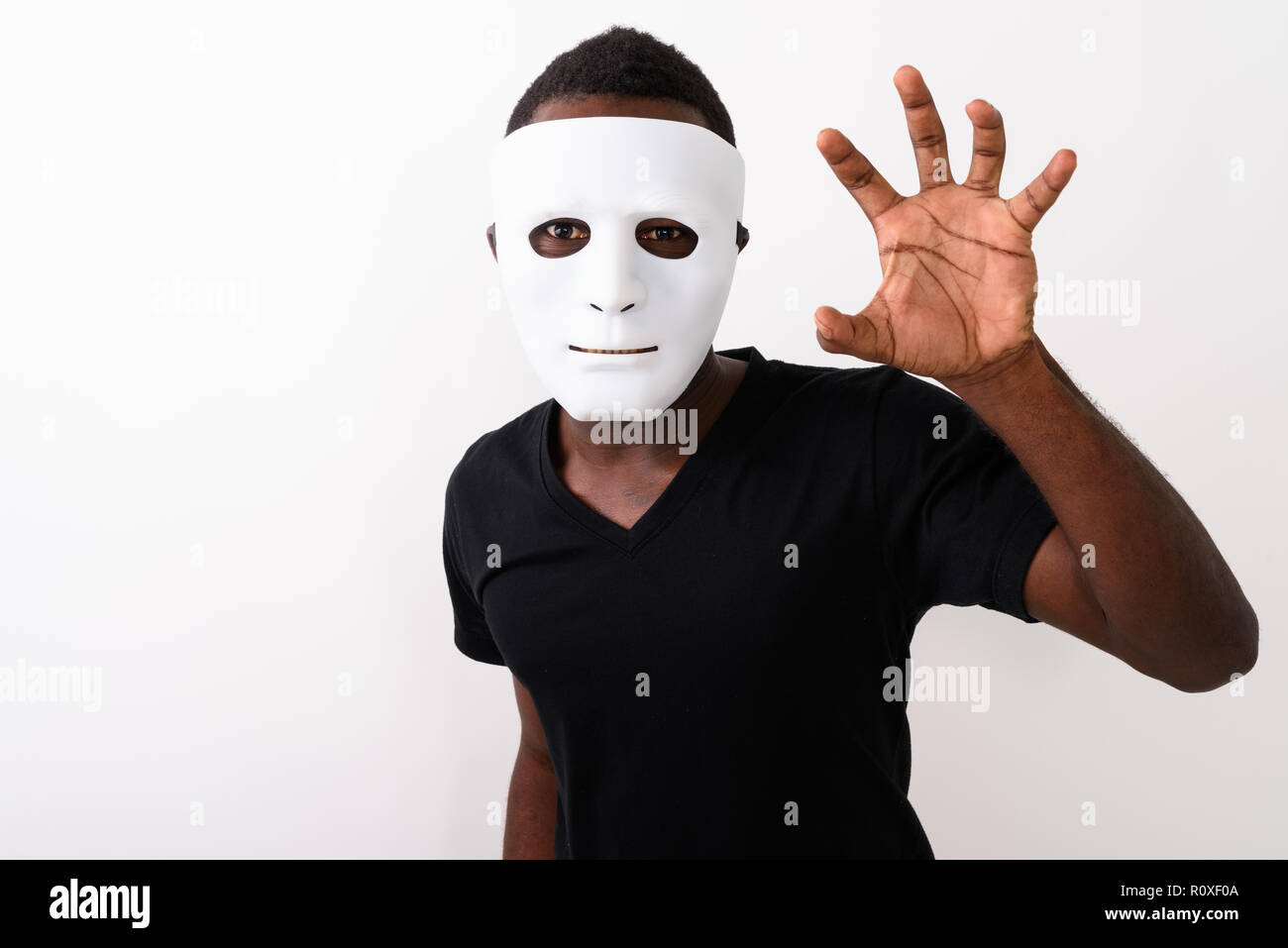 Studio shot del giovane africano nero uomo che indossa la maschera e mostra Foto Stock