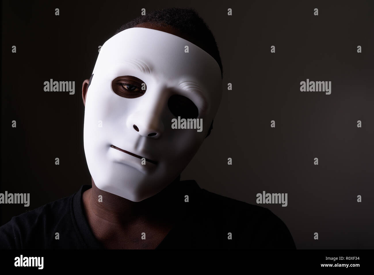 Ritratto di giovane africano nero uomo in camera oscura che indossa la maschera Foto Stock