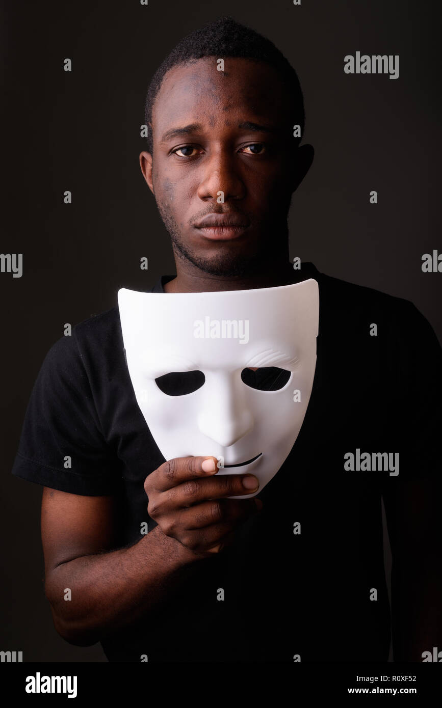 Ritratto di giovane africano nero uomo in camera oscura maschera di contenimento Foto Stock