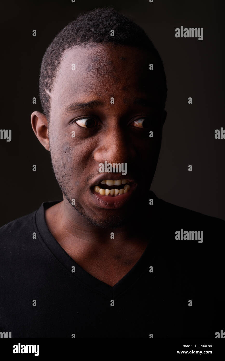 Studio shot di Angry Young Africano nero uomo urlando nel buio r Foto Stock