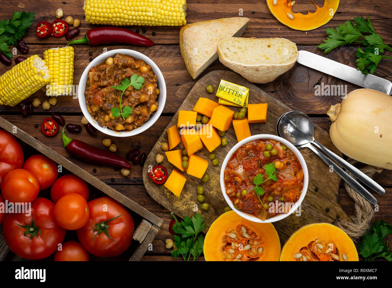 Due Winter Warmer stufati circondato da ingredienti overhead shot: zucca stufato e chili con carne Foto Stock