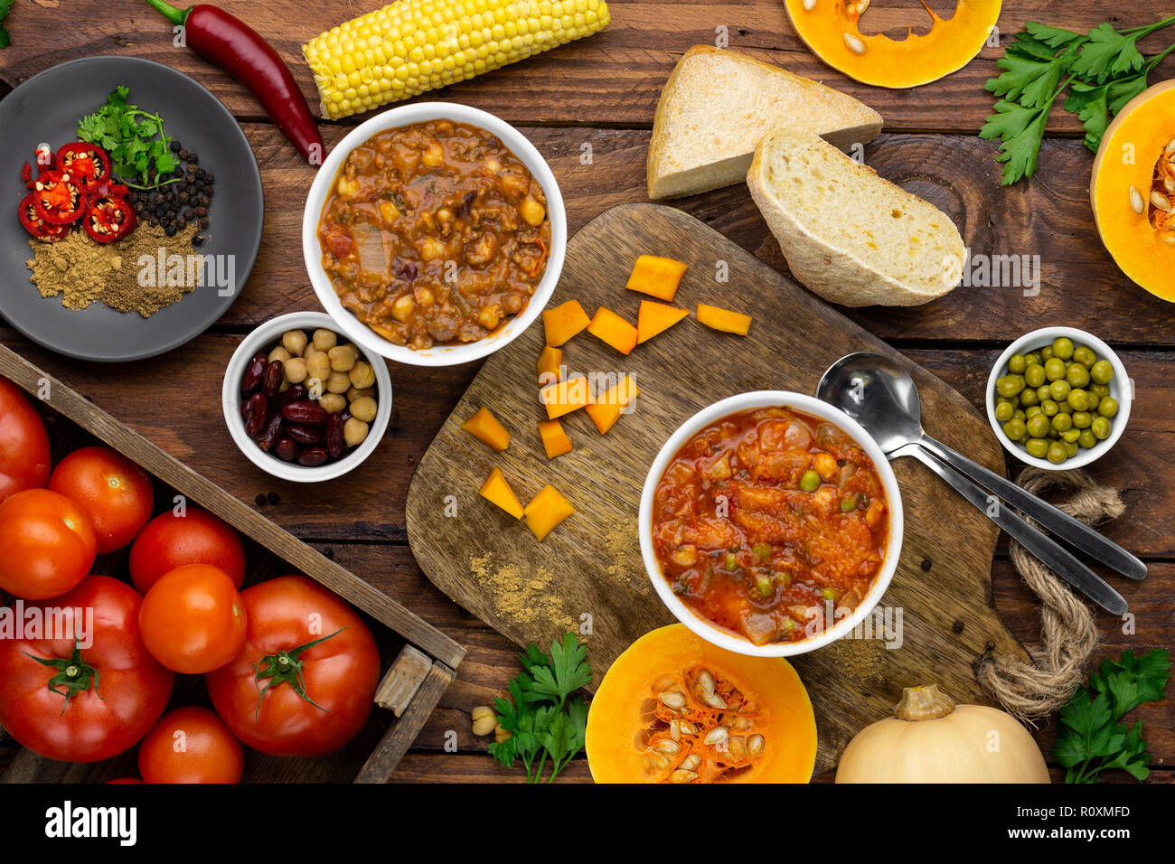 Due Winter Warmer stufati circondato da ingredienti overhead shot: zucca stufato e chili con carne Foto Stock