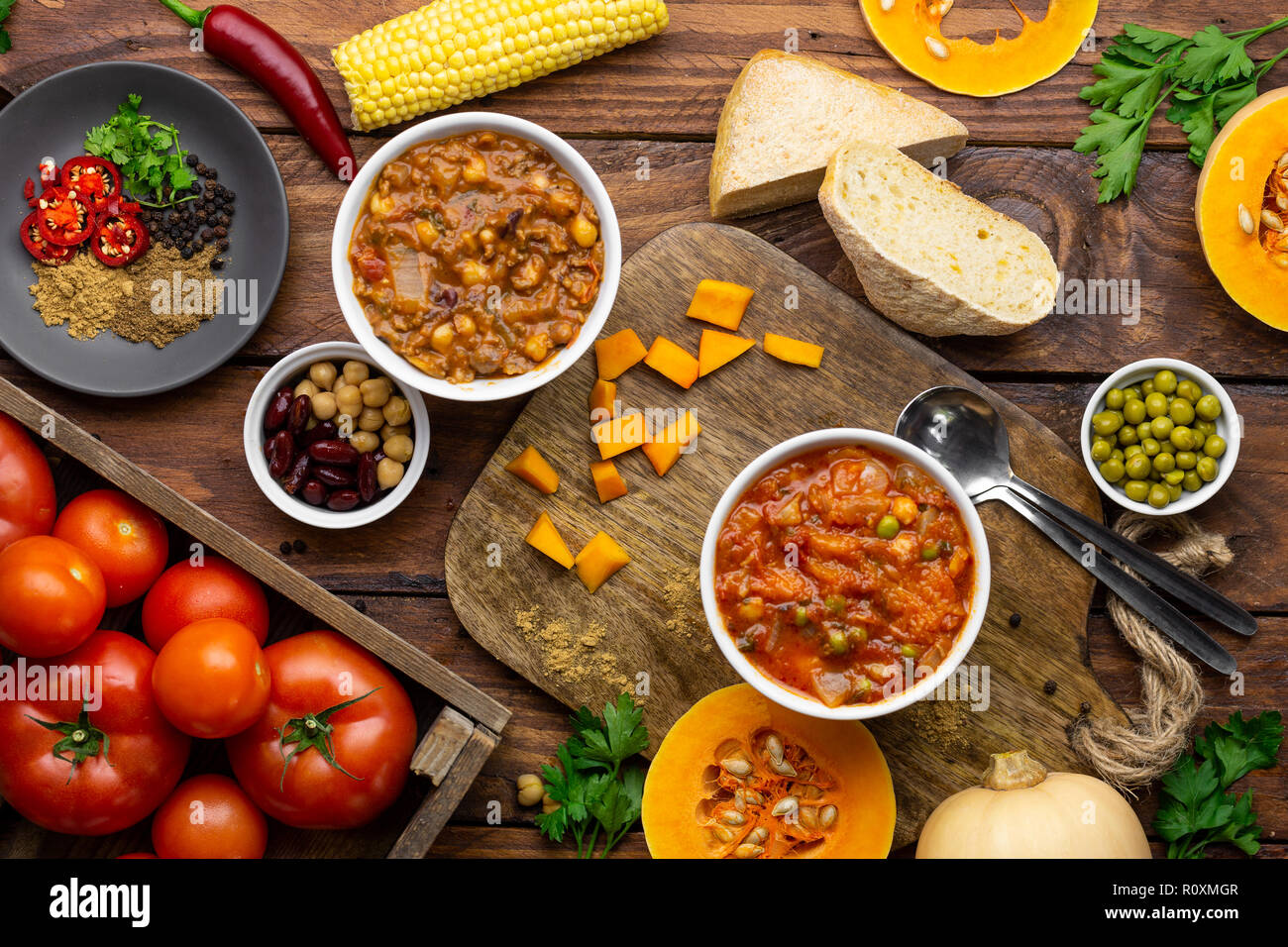 Due Winter Warmer stufati circondato da ingredienti overhead shot: zucca stufato e chili con carne Foto Stock