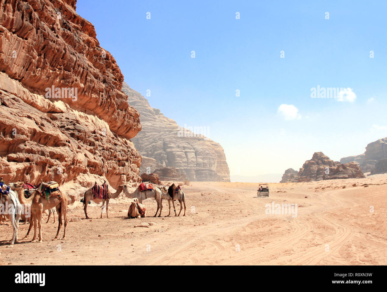 Il safari in jeep a Wadi Rum desert, Giordania. I cammelli e i turisti in giro in macchina su off-road sulla sabbia tra le splendide rocce Foto Stock