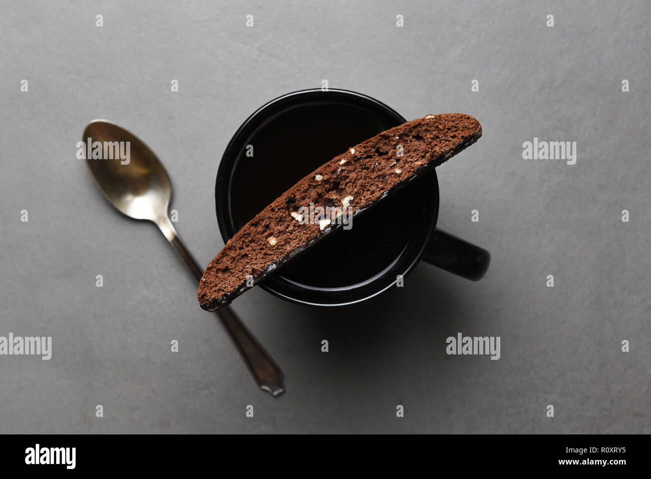 Vista aerea di biscotti al cioccolato sul bordo di una tazza di caffè su un grigio ardesia tabella. Foto Stock