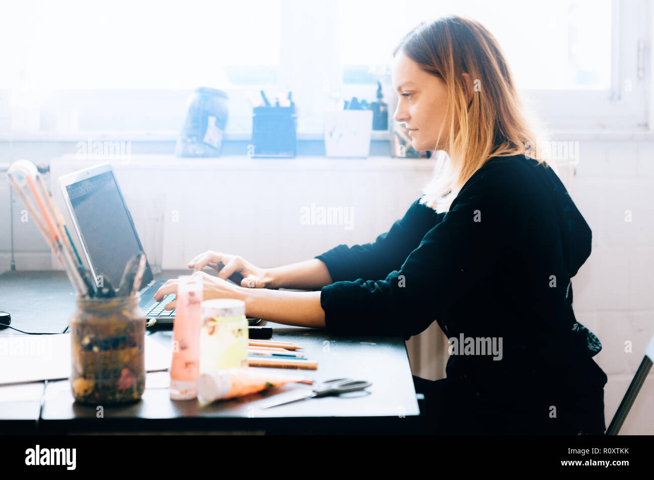 Femmina professionale designer che lavora nel suo studio seduto davanti a un computer portatile Foto Stock