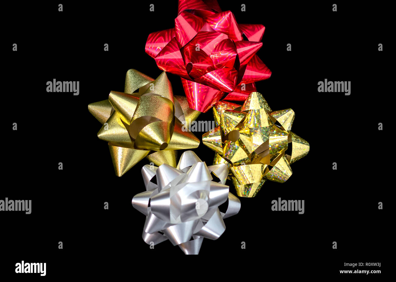 Quattro (4) Natale in satin nastri di raso - Oro olografica, rosso, oro e di colore bianco su sfondo nero. Camera per copia. Foto Stock