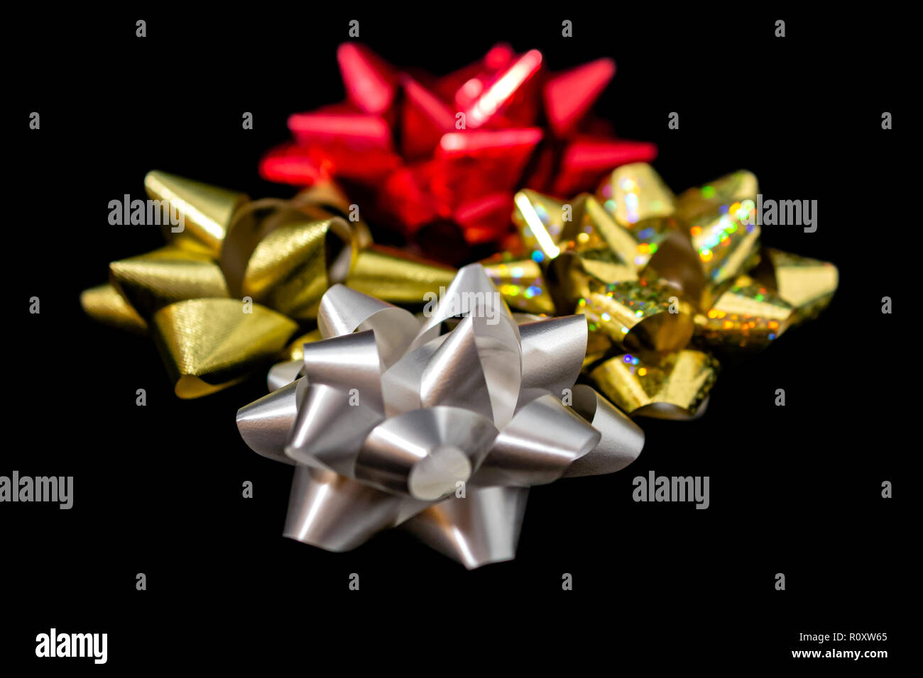 Quattro (4) Natale in satin nastri di raso - Oro olografica, rosso, oro e di colore bianco su sfondo nero. Camera per copia. Foto Stock