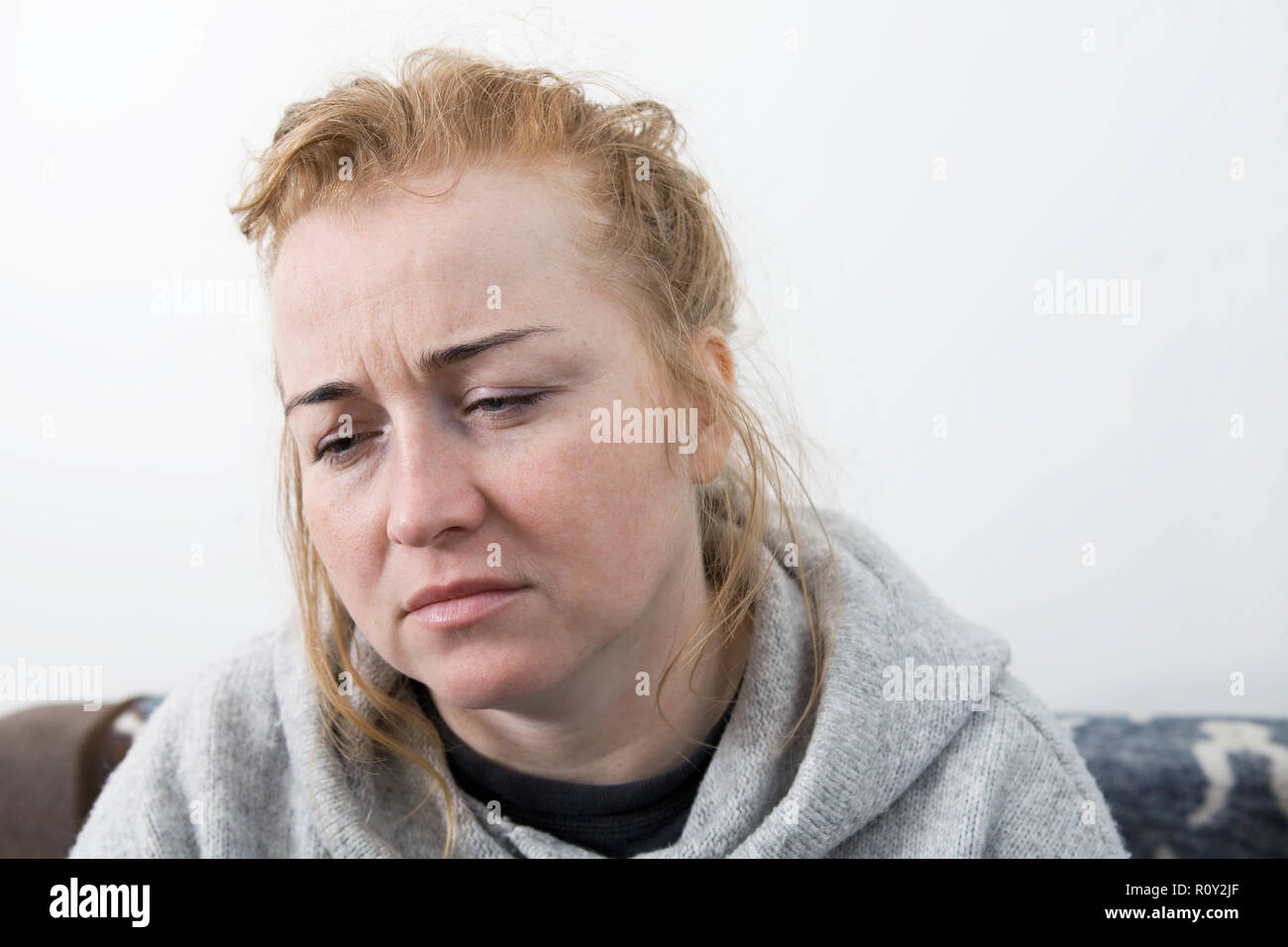 Malati e stanchi donna con un mal di testa seduto su un divano per chiedere aiuto. Primo piano verticale. Foto Stock