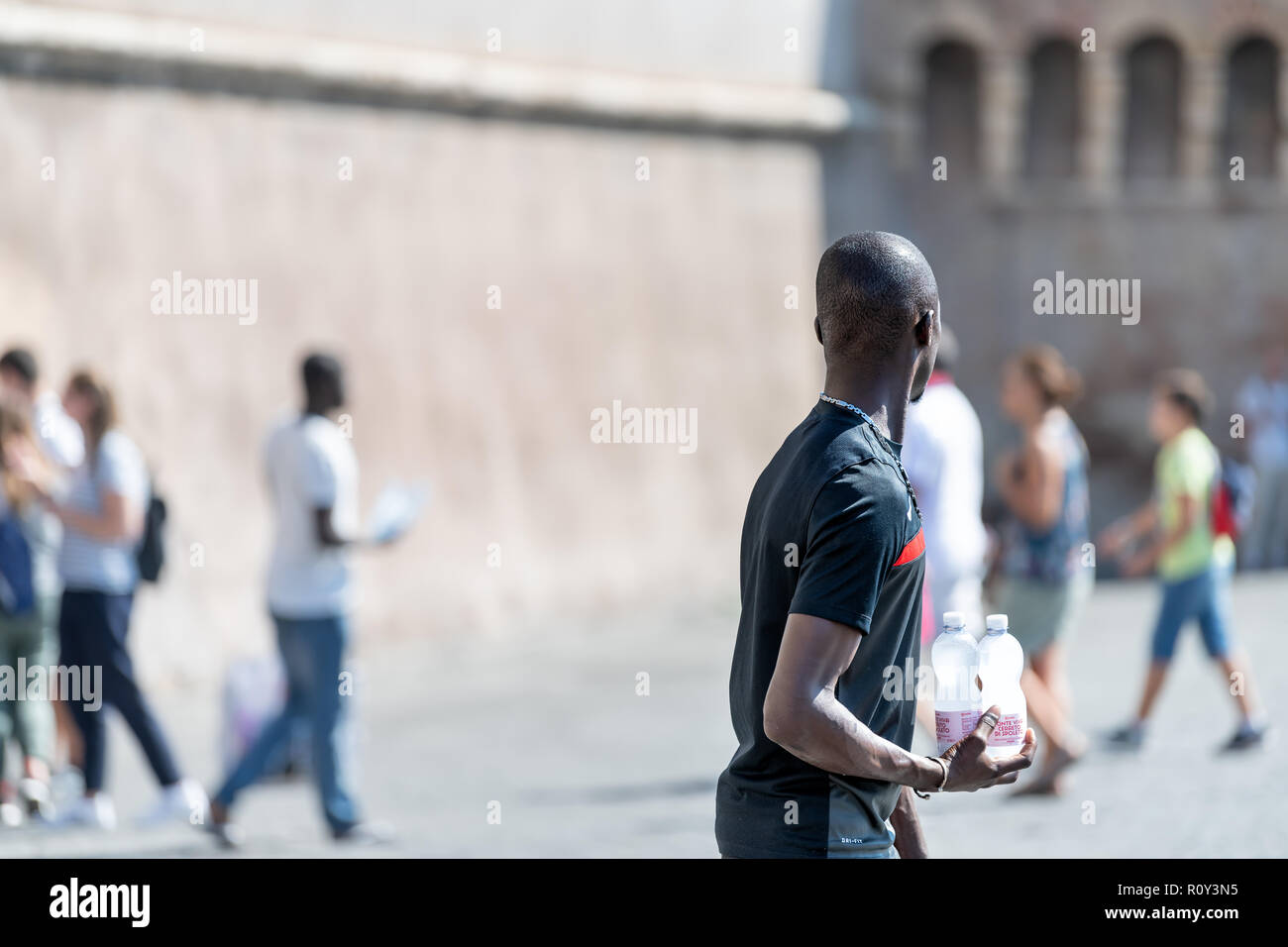Roma, Italia - 5 Settembre 2018: africano maschio nero, uomo, l immigrato, venditore ambulante, venditore vendita di imbottigliamento di bottiglie di acqua, strada a piedi il marciapiede wit Foto Stock