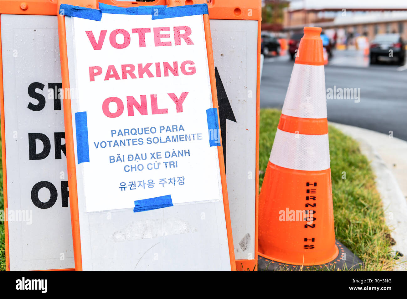 Herndon, Stati Uniti d'America - 6 Novembre 2018: parcheggio degli elettori qui segno in alta scuola stazione di polling con la freccia sul marciapiede, strada in coreano, spagnolo, vietnamita e Foto Stock