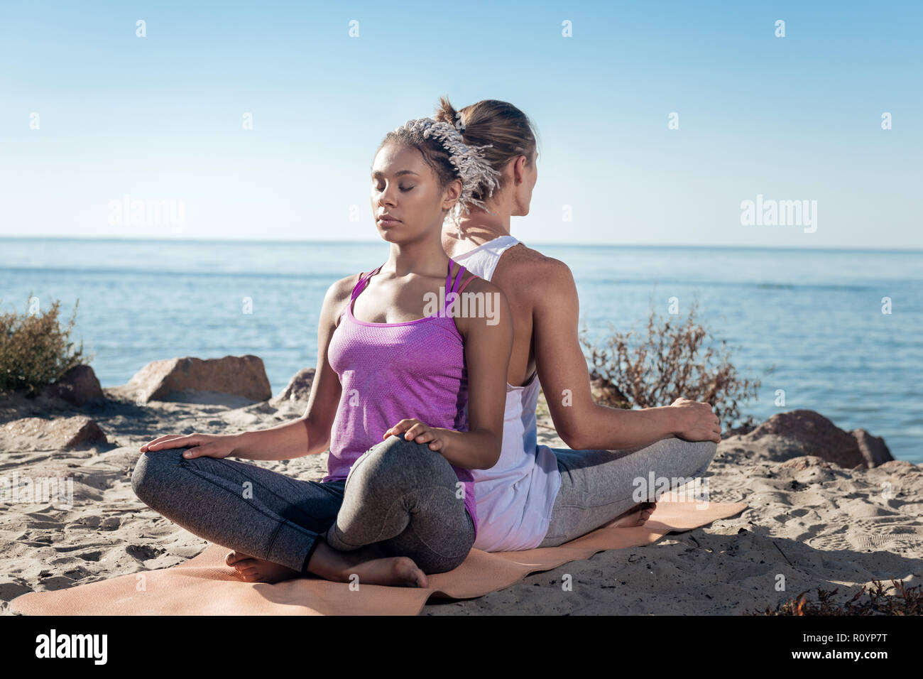 Donna con dreadlocks meditando insieme con il suo fidanzato vicino al fiume Foto Stock