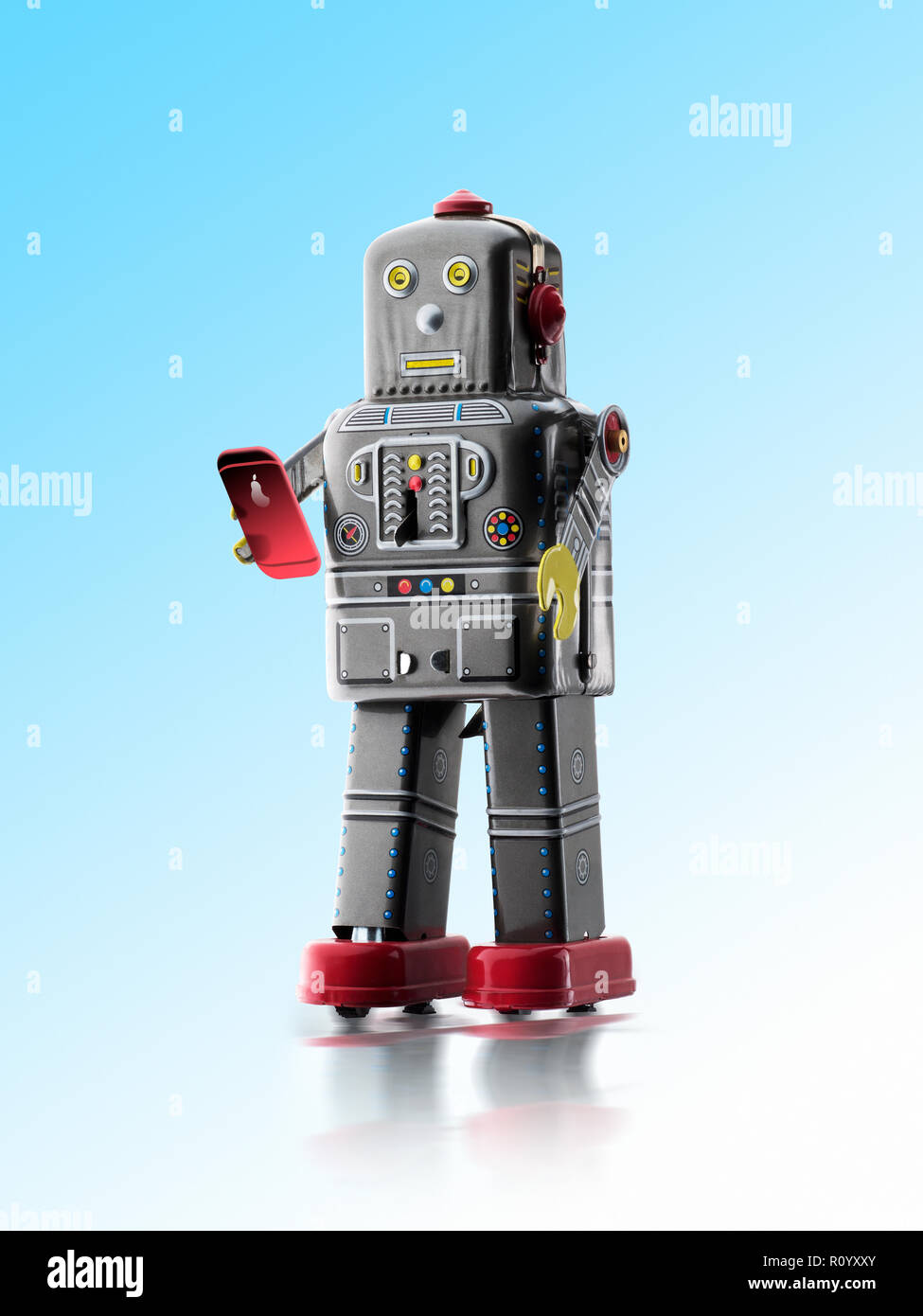 Vintage retrò wind-up tin robot giocattolo texting sullo smartphone, studio shot Foto Stock