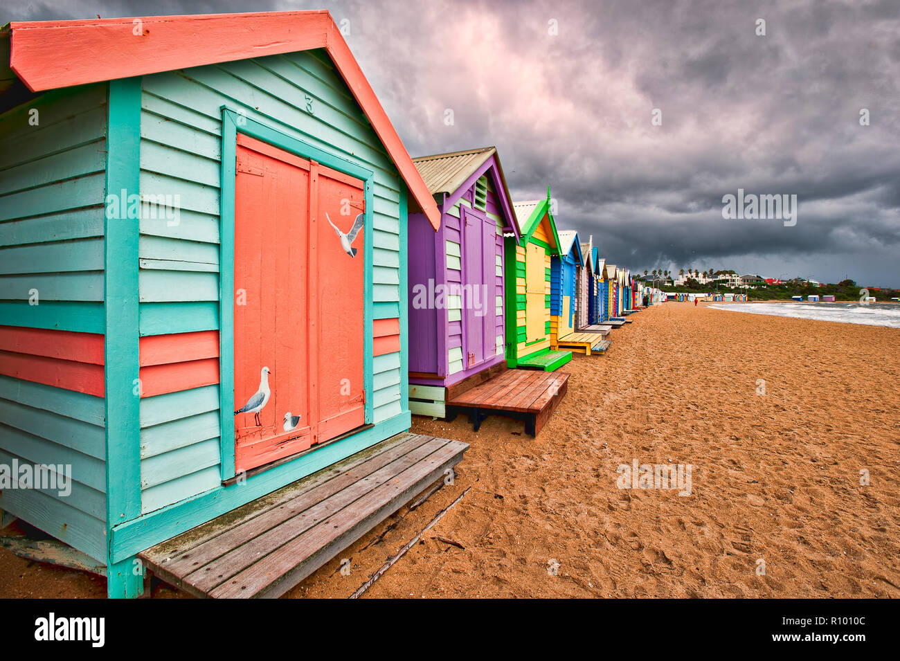 Una tempesta si avvicina la colorata e iconica spiaggia capanne sulla Spiaggia di Brighton vicino a Melbourne in Victoria, Australia. Foto Stock