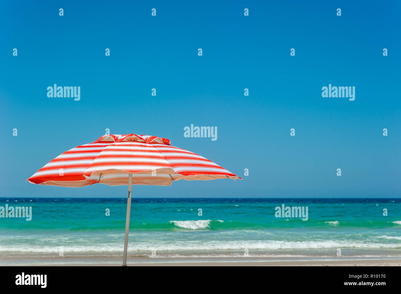 La mia a strisce rosse e bianche ombrellone da spiaggia si erge come un simbolo iconico di una spiaggia lo stile di vita e cultura sul Surfer's Paradise Beach a Gold Coast. Foto Stock