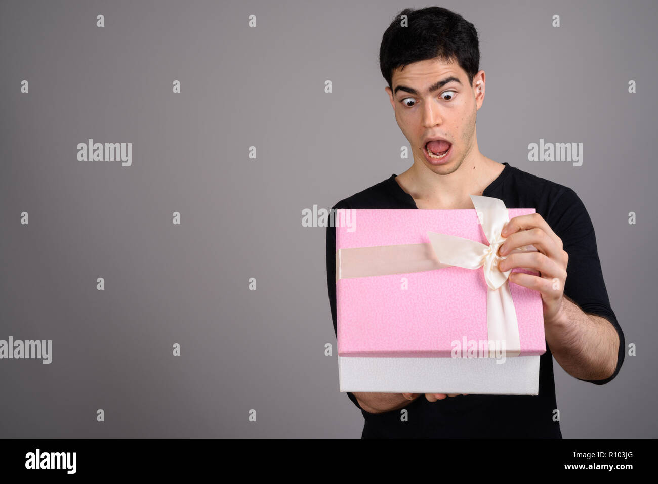 Ritratto di giovane uomo bello contro uno sfondo grigio Foto Stock