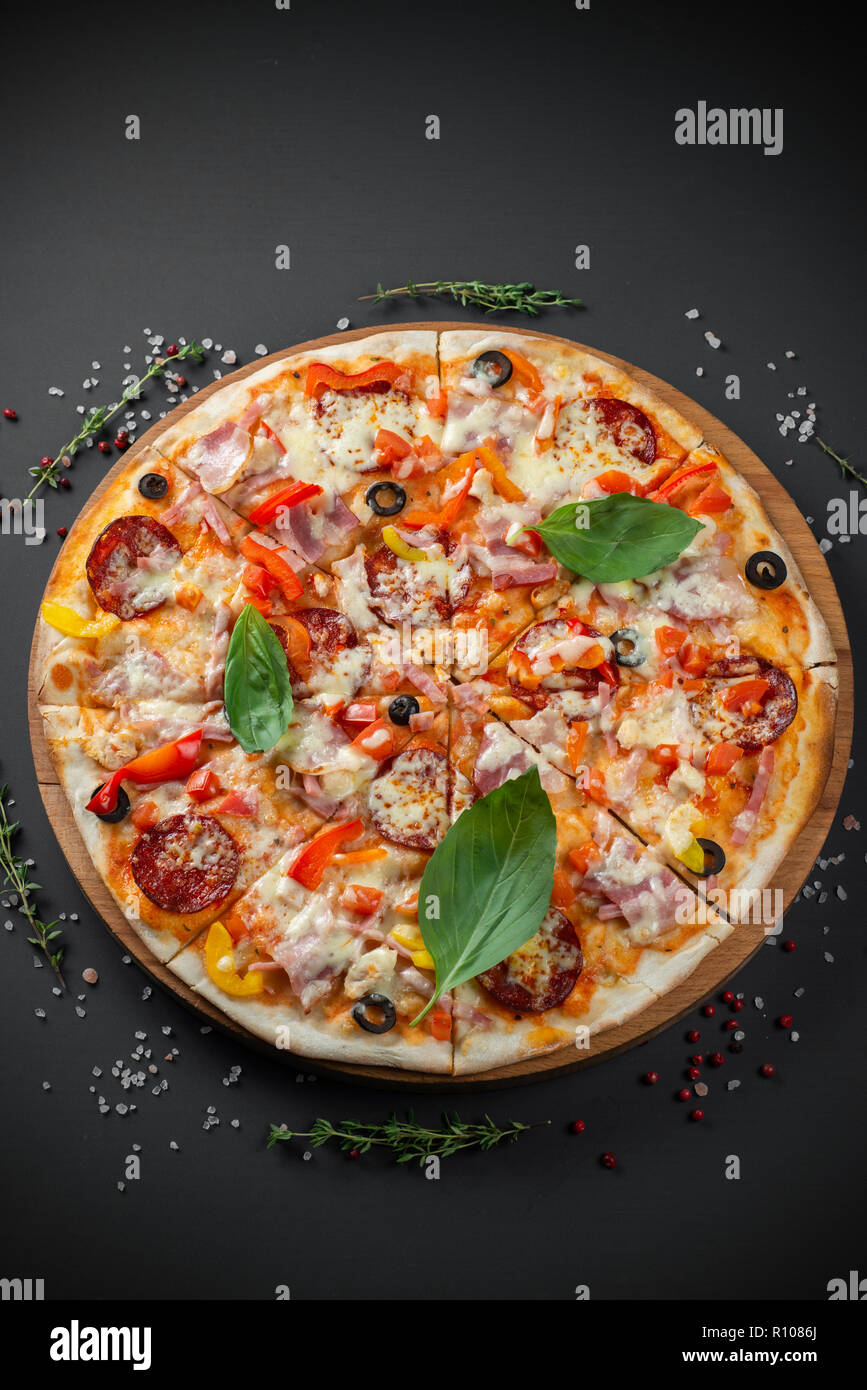 Pizza con salsiccia e basilico su sfondo scuro Foto Stock