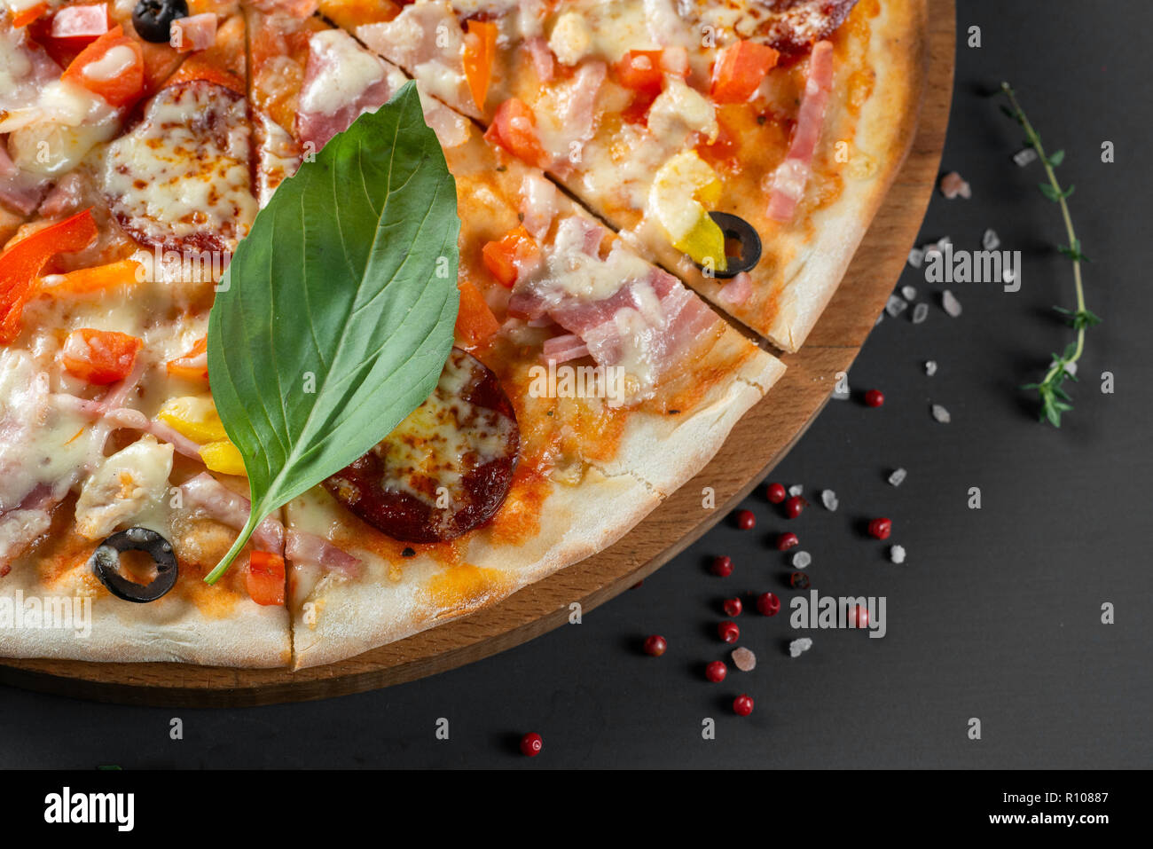Pizza con salsiccia e basilico su sfondo scuro Foto Stock