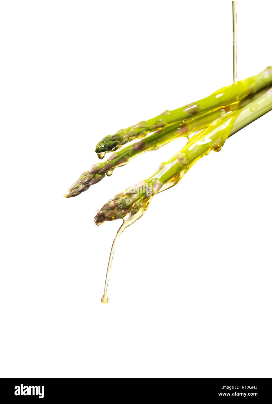 Versare olio su asparagi spears, sfondo semplice Foto Stock